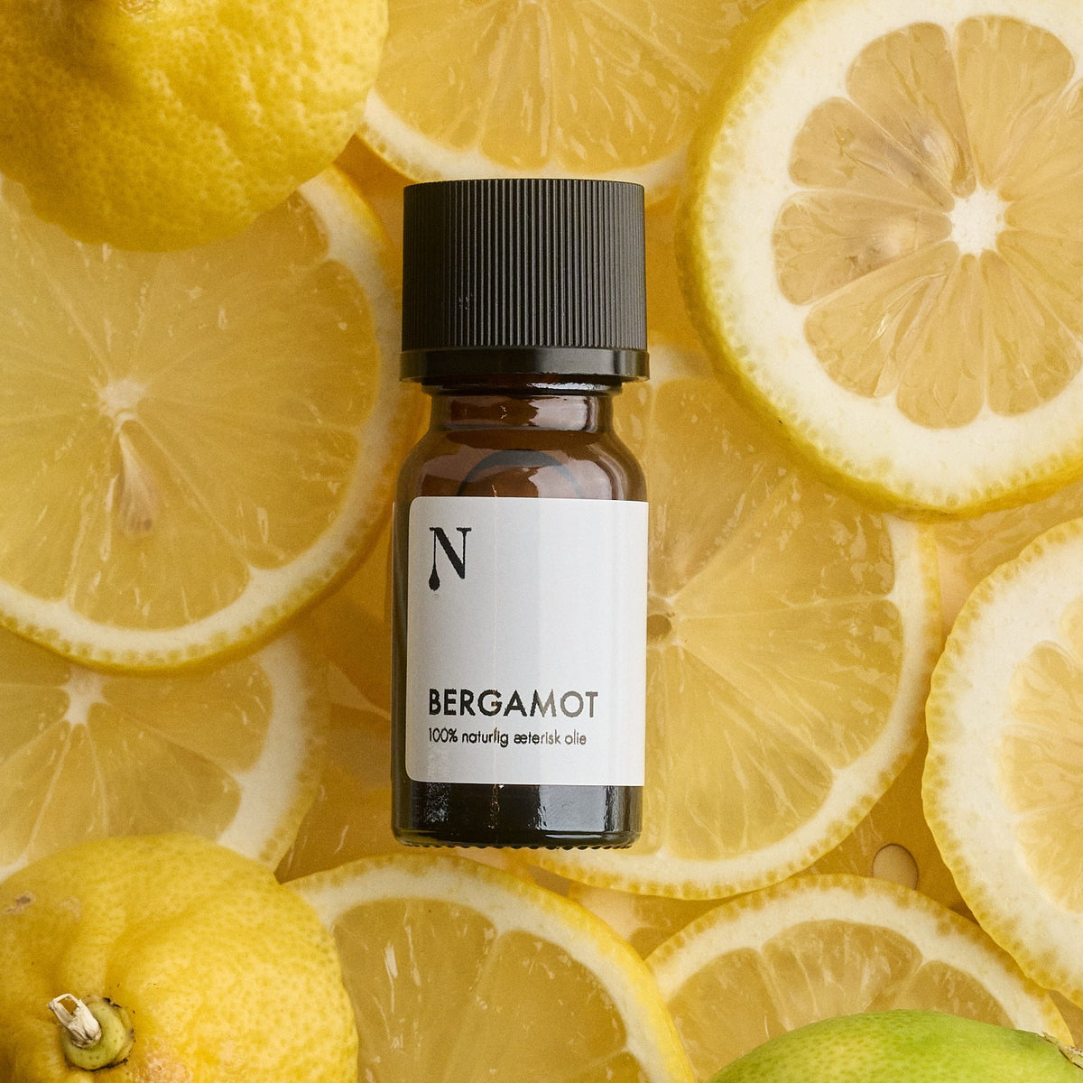 Flaske med bergamotolie på skiver af bergamot og citrus