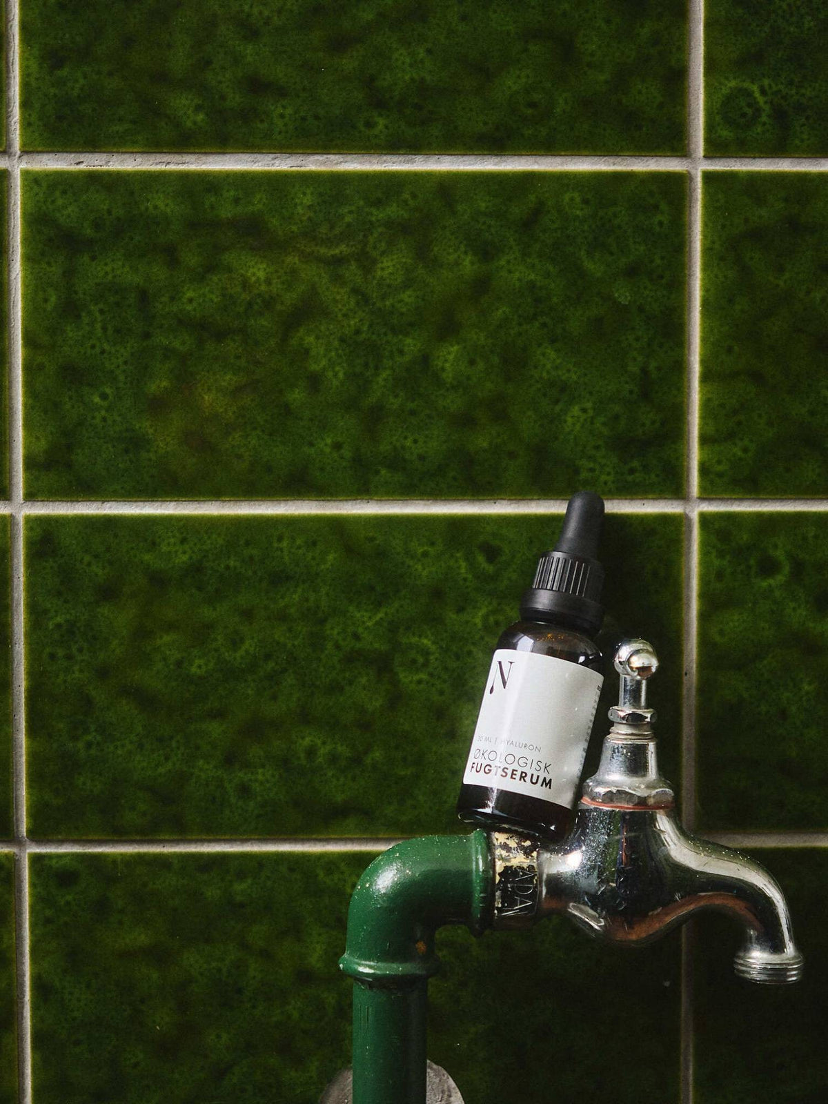 Økologisk Fugtserum på vandhanen foran grønne fliser