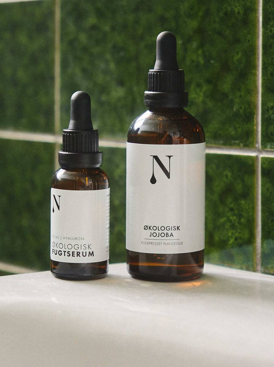 Økologisk Jojobaolie og Fugtserum på håndvasken foran grønne fliser