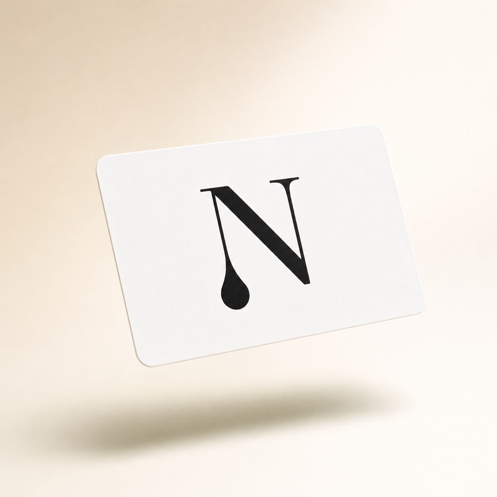 Hvidt gavekort fra Naturligolie med det sorte N-logo, svævende på skrå foran en lys beige studiebaggrund