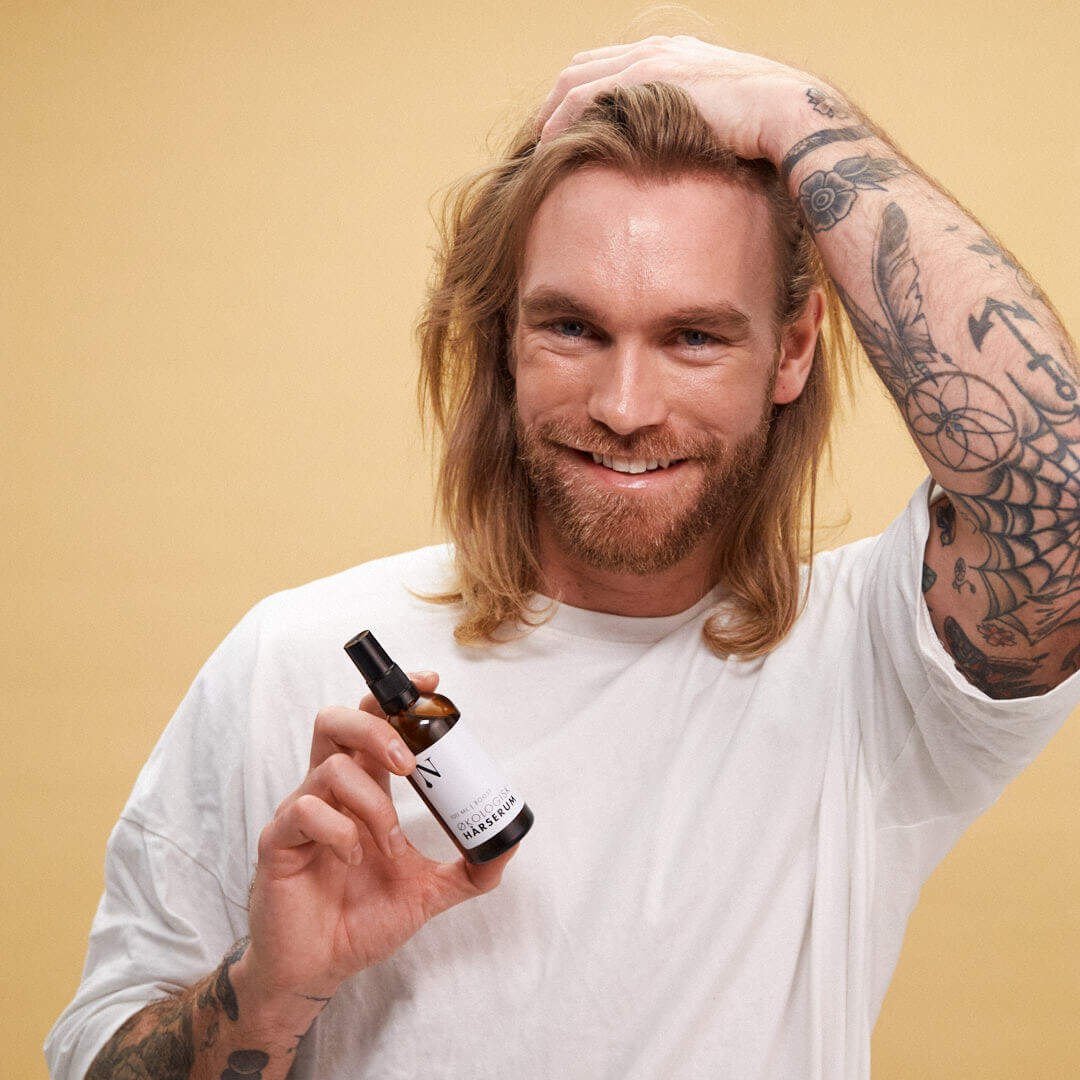 Mand med langt hår holder Naturligolie Økologisk Hårserum mod hårtab