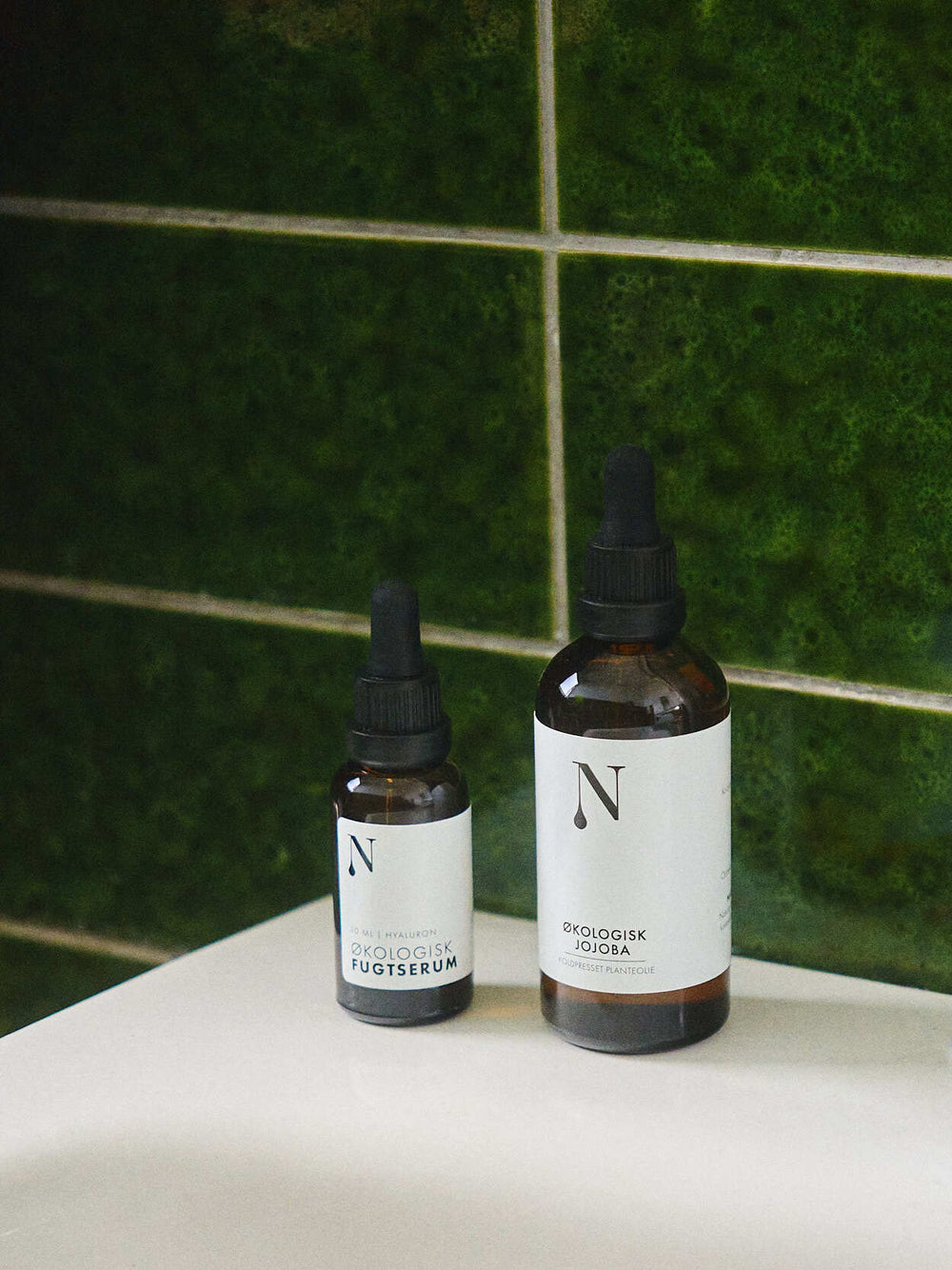 Fugtserum og Jojobaolie på et grønt badeværelse
