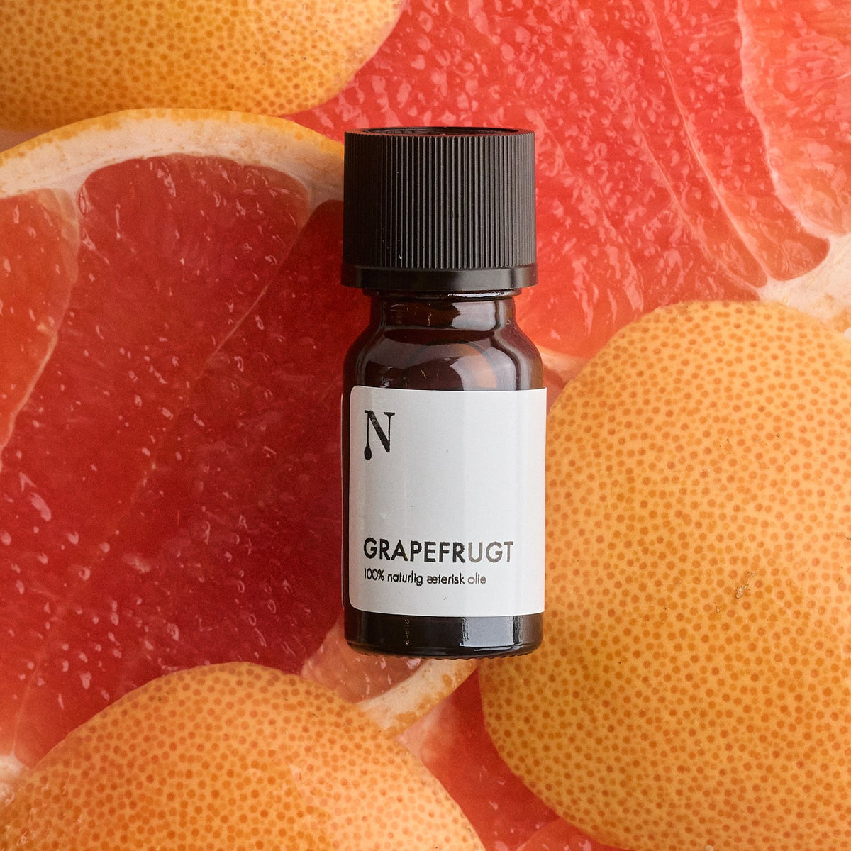 Flaske med grapefrugtolie på stykker af grapefrugt