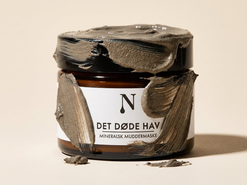 Naturligolie Mineralsk Mudder i krukke med mudder smurt ud over låg og etiket